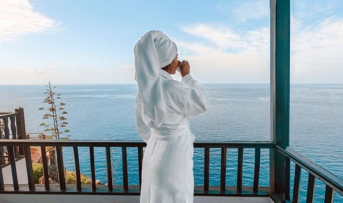 Person genießt den Blick auf den Atlantischen Ozean von der Terrasse eines Zimmers im Hotel Jardín Tecina auf La Gomera